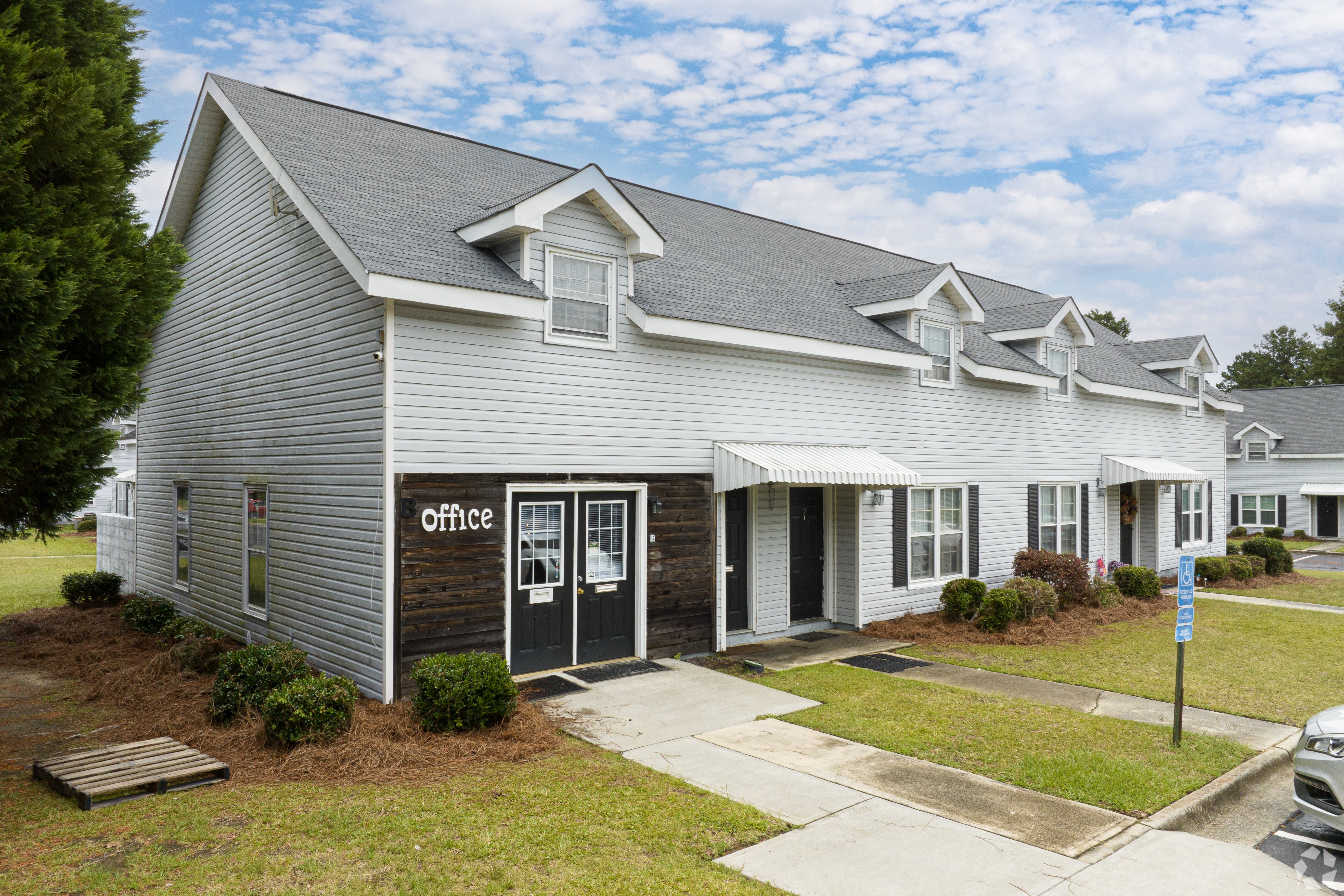 a white building with a gray roof and a blue sign that reads office